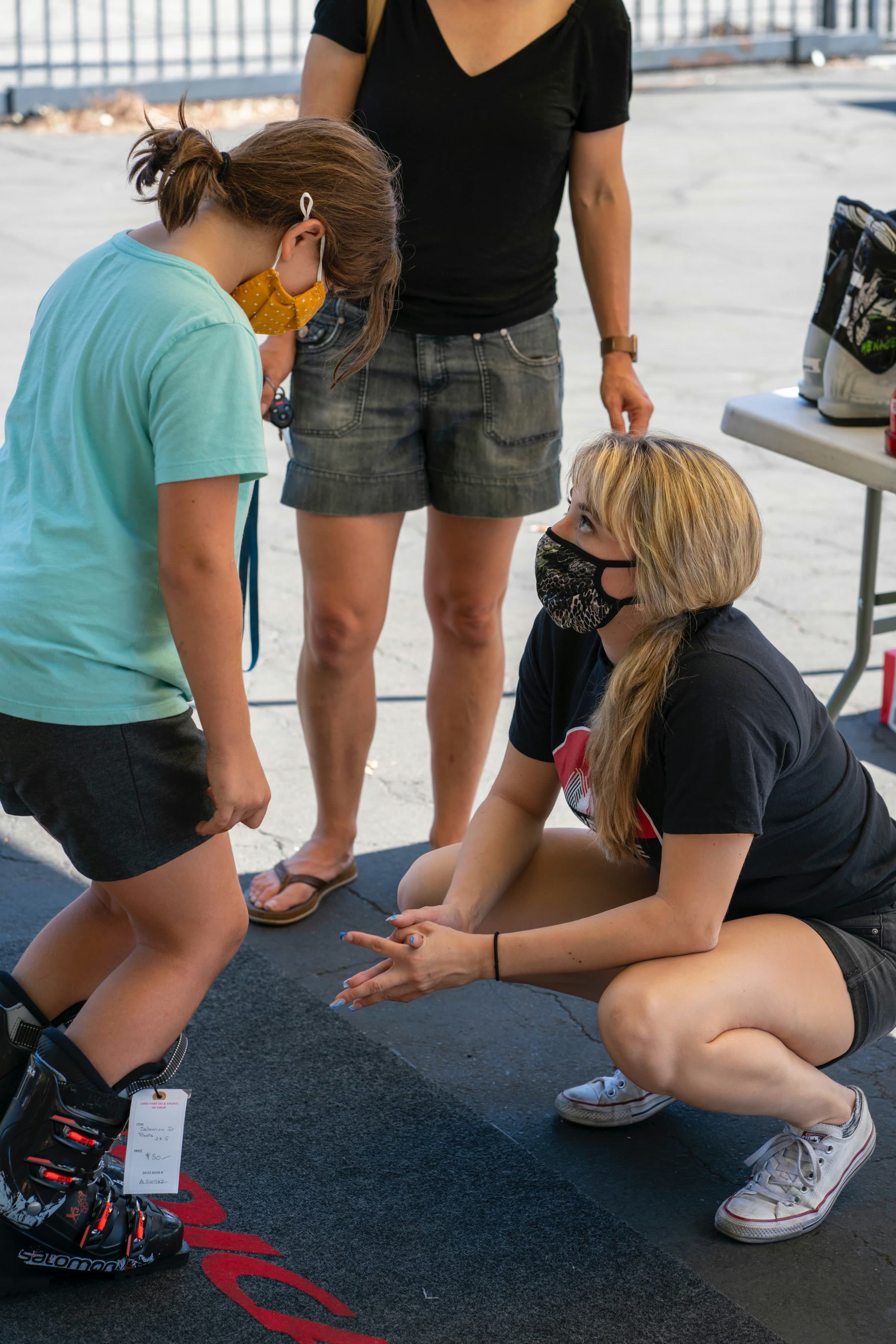 A staffer fitting a kid's ski boots